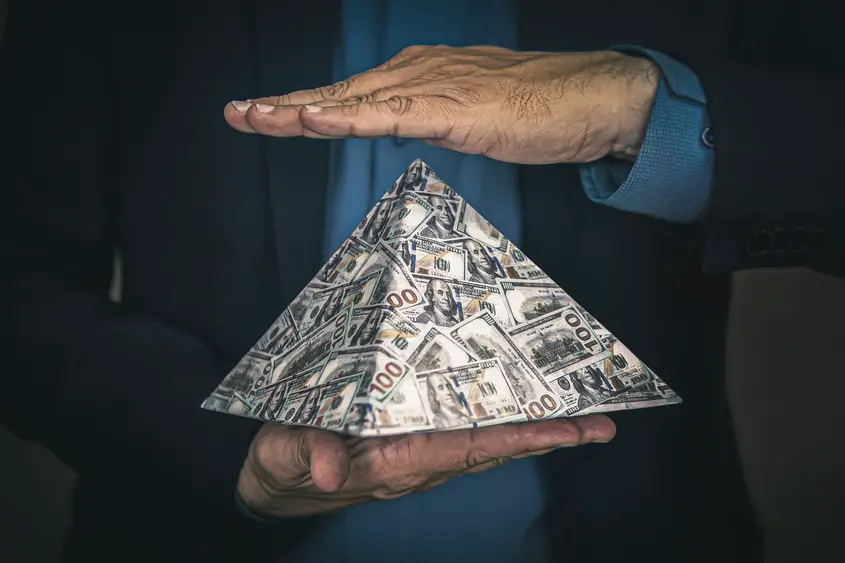 Are NFTs a pyramid scheme? A pyramid made from money, signifying that pyramid schemes are nothing more than a cash grab.
