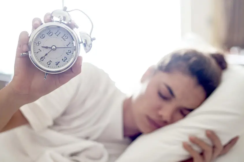 Woman holding an alarm clock as to say it's still early in the NFT space.